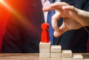 Homem de terno e gravata ameaçando derrubar uma peça que simboliza um chefe.